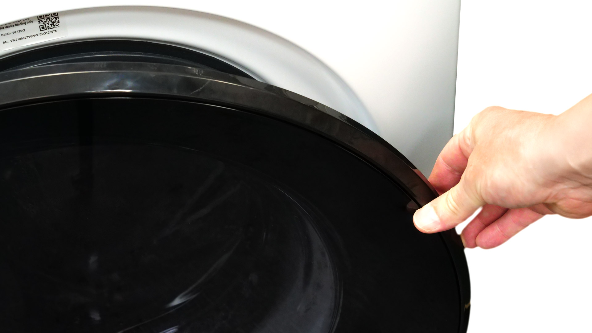 Eine Hand greift die runde Tür der Waschmaschine, um sie zu öffnen.