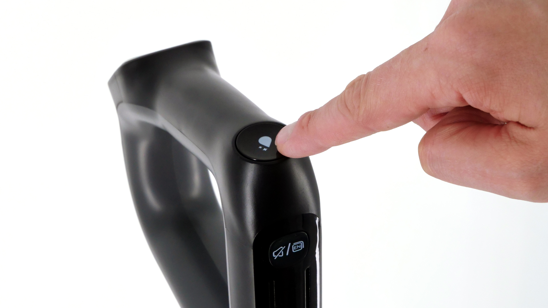 Ein Finger betätigt eine Taste am Handteil, die mit dem Symbol eines Wassertropfens beschriftet ist.