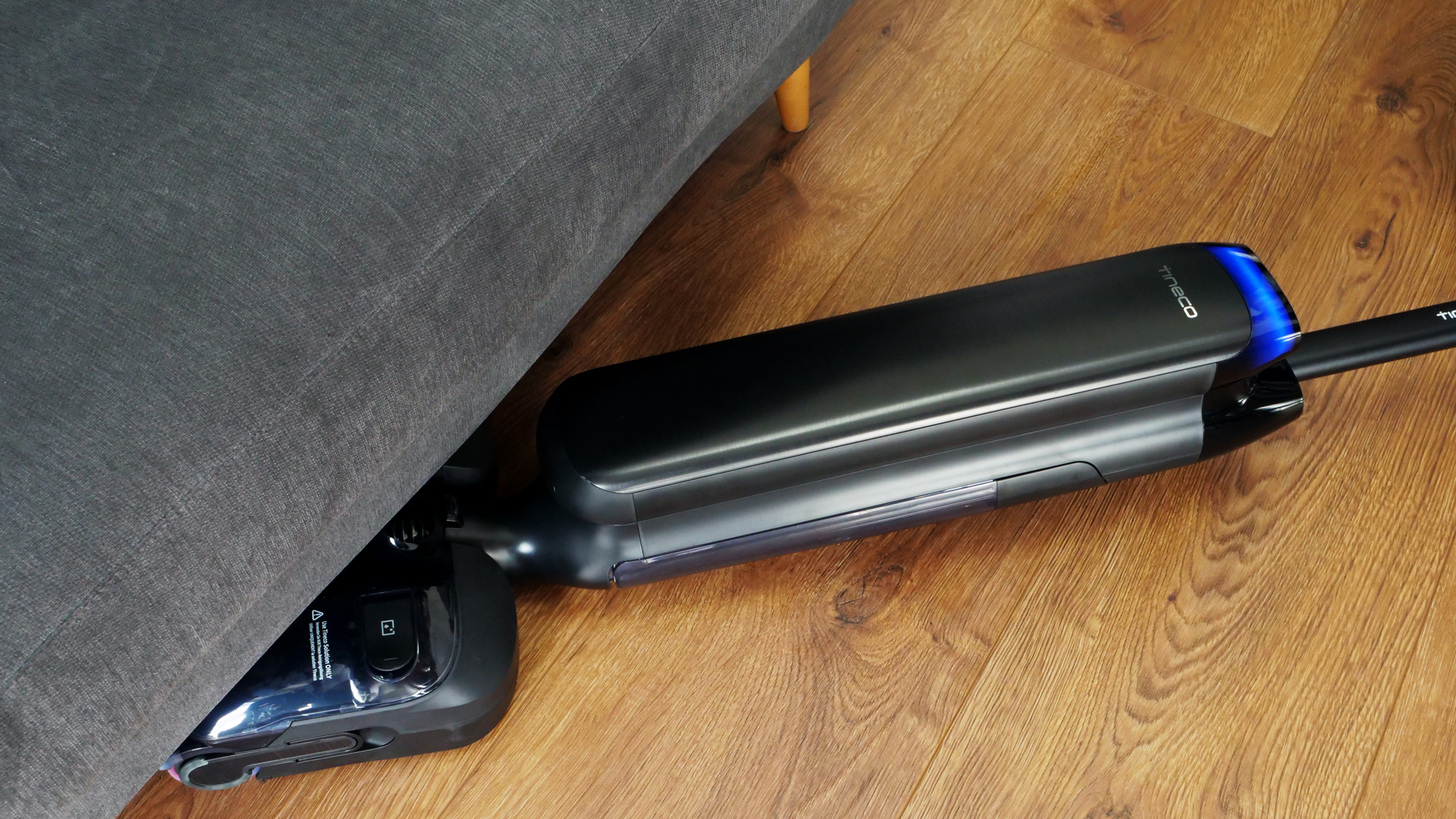 Das Modell wird unter ein Sofa geschoben. Dabei liegt es parallel zum Fußboden.